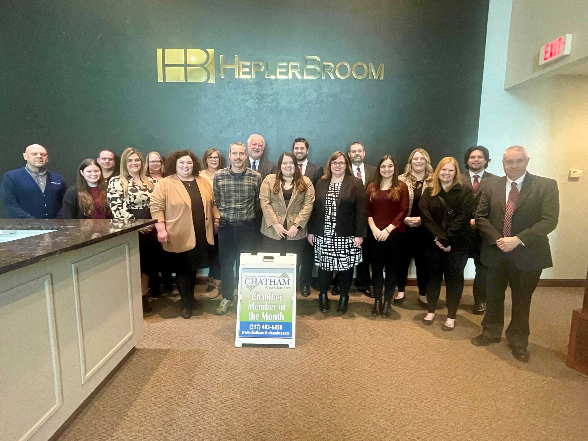 group of people standing in front of a sign that reads HB HeplerBroom
