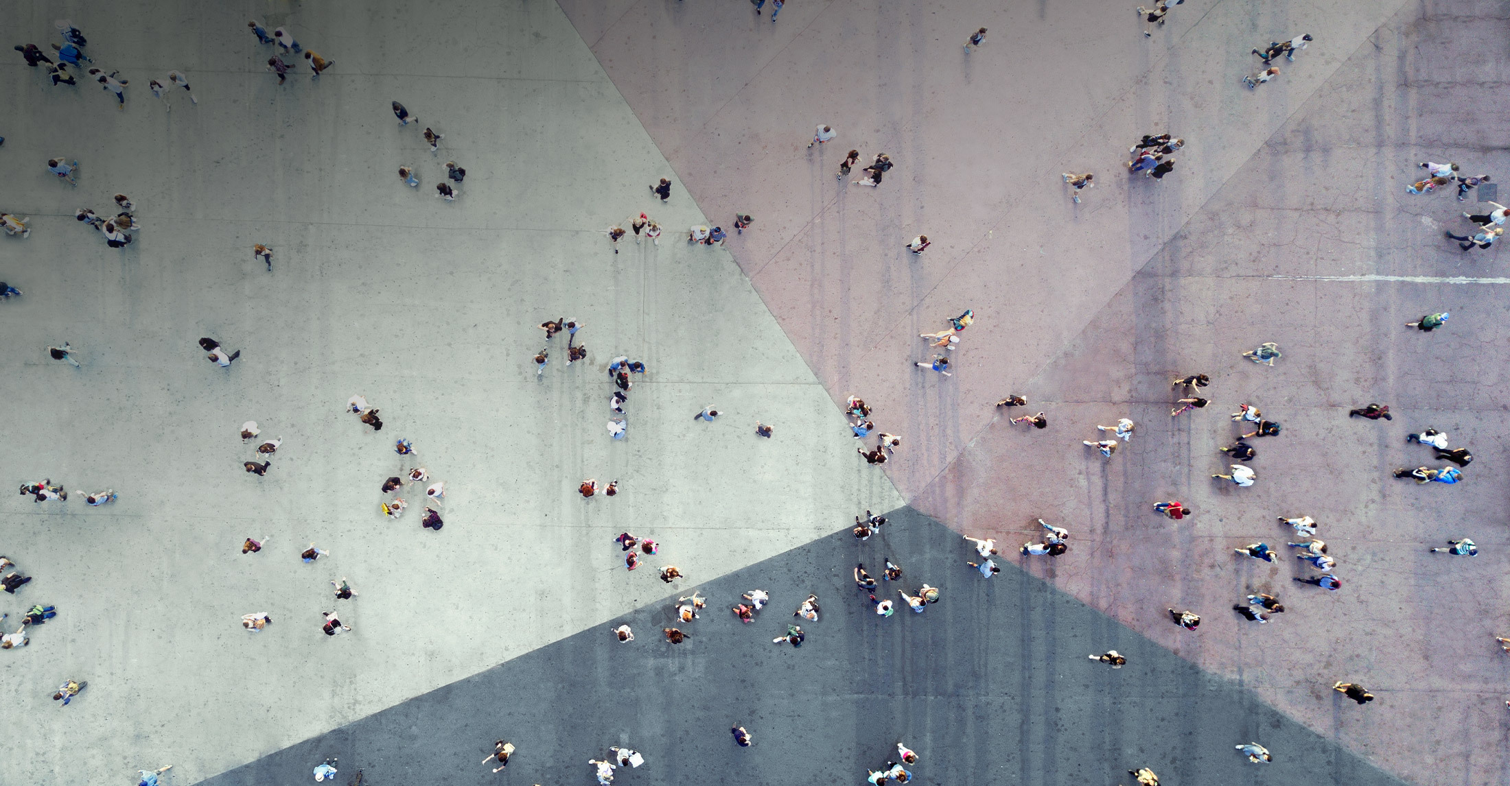 aerial view of large space where people are individually walking or standing in small groups