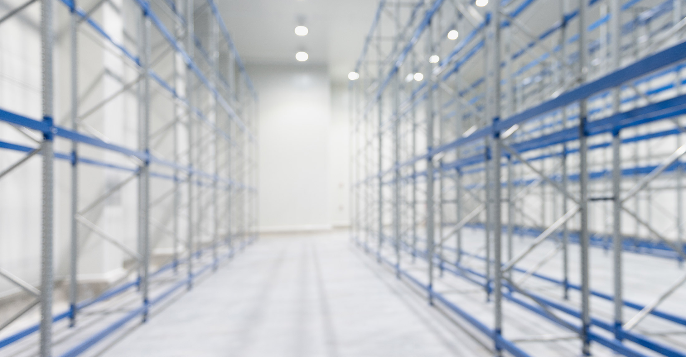 office building hallway with floor to ceiling windows on both sides and rows of grey and blue scaffolding in front of windows