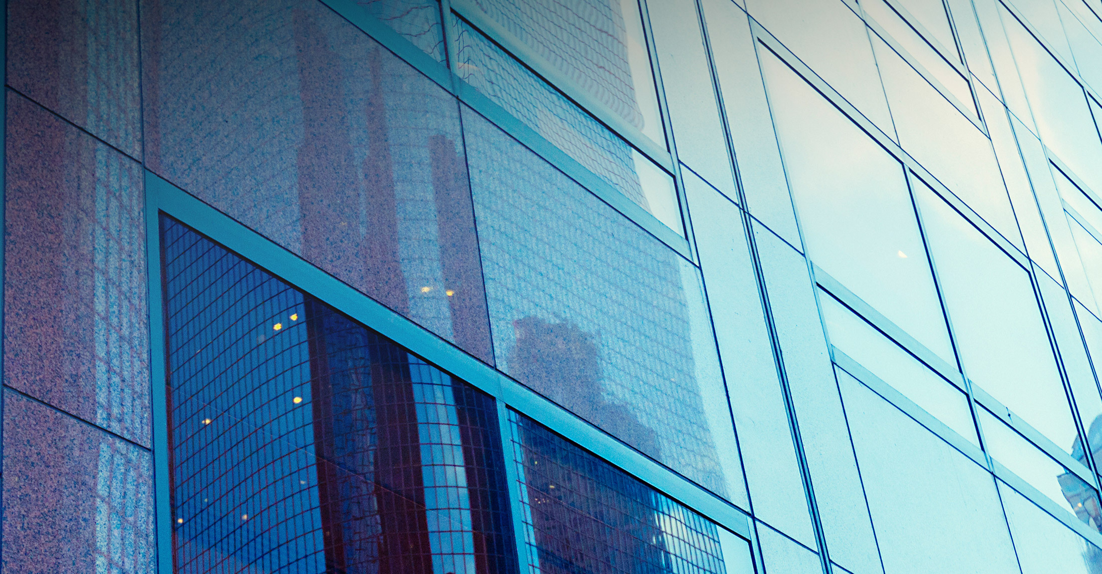 Close up view of an abstract building with brown granite on the left and office windows to the right.