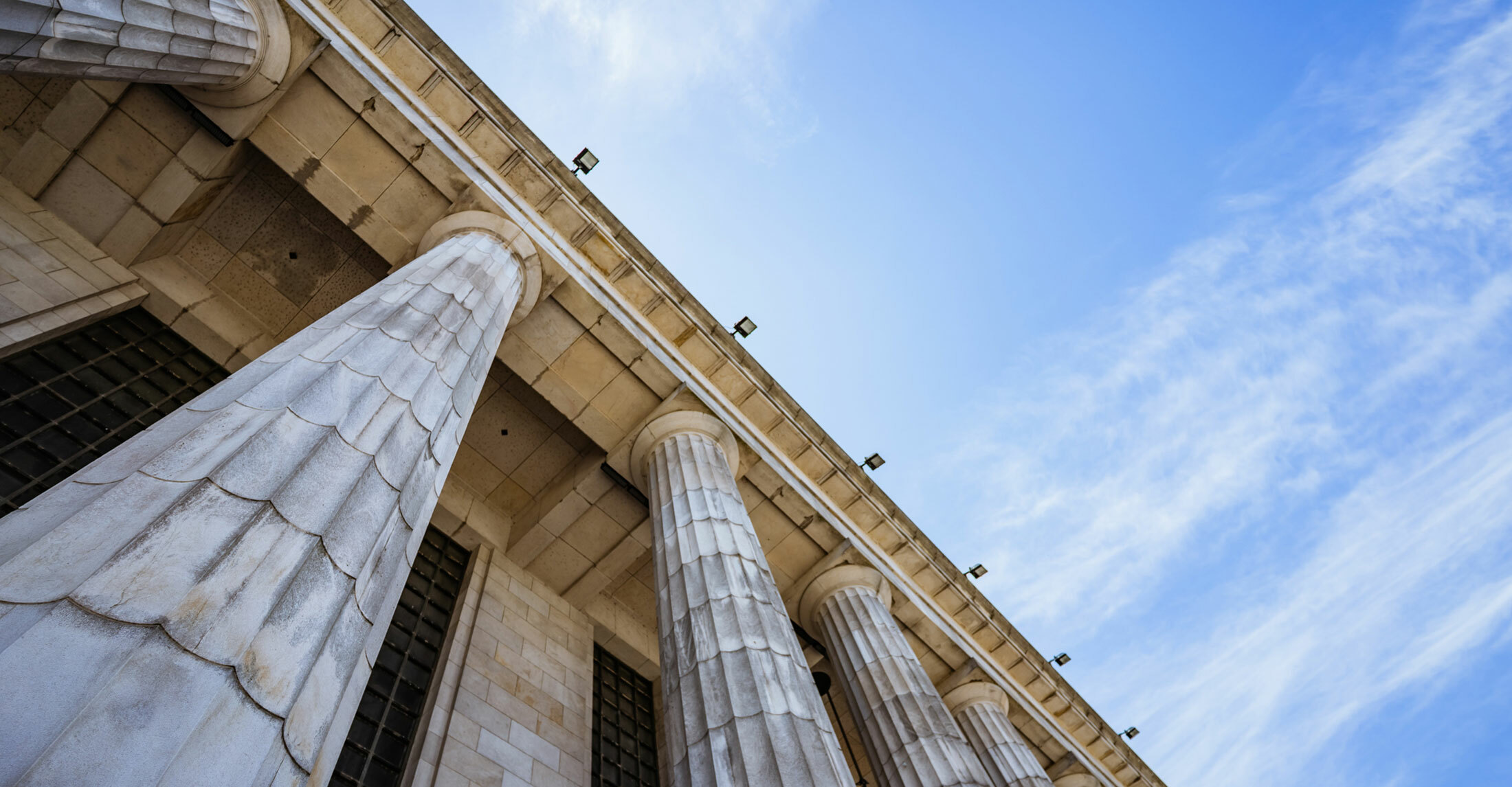 outside top portion of a multi-story building with a Greek inspired doric columns.