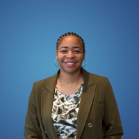 African-American woman wearing a brown suit jacket and patterned jewel neck blouse